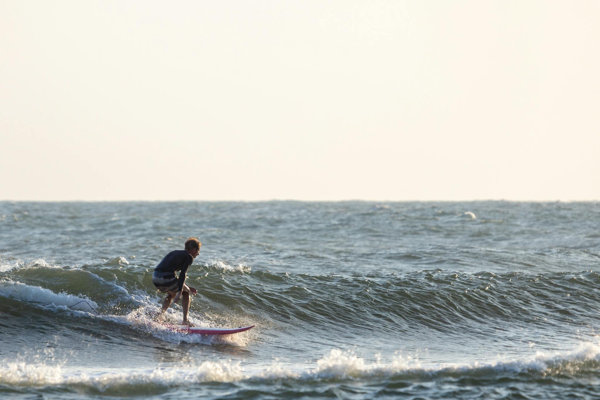 A lone surfer skillfully rides a wave on a sunny ocean day.