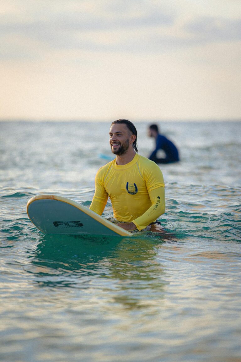 A man in a yellow wetsuit surfing at sunset in Tel Aviv, Israel's Mediterranean coast.
